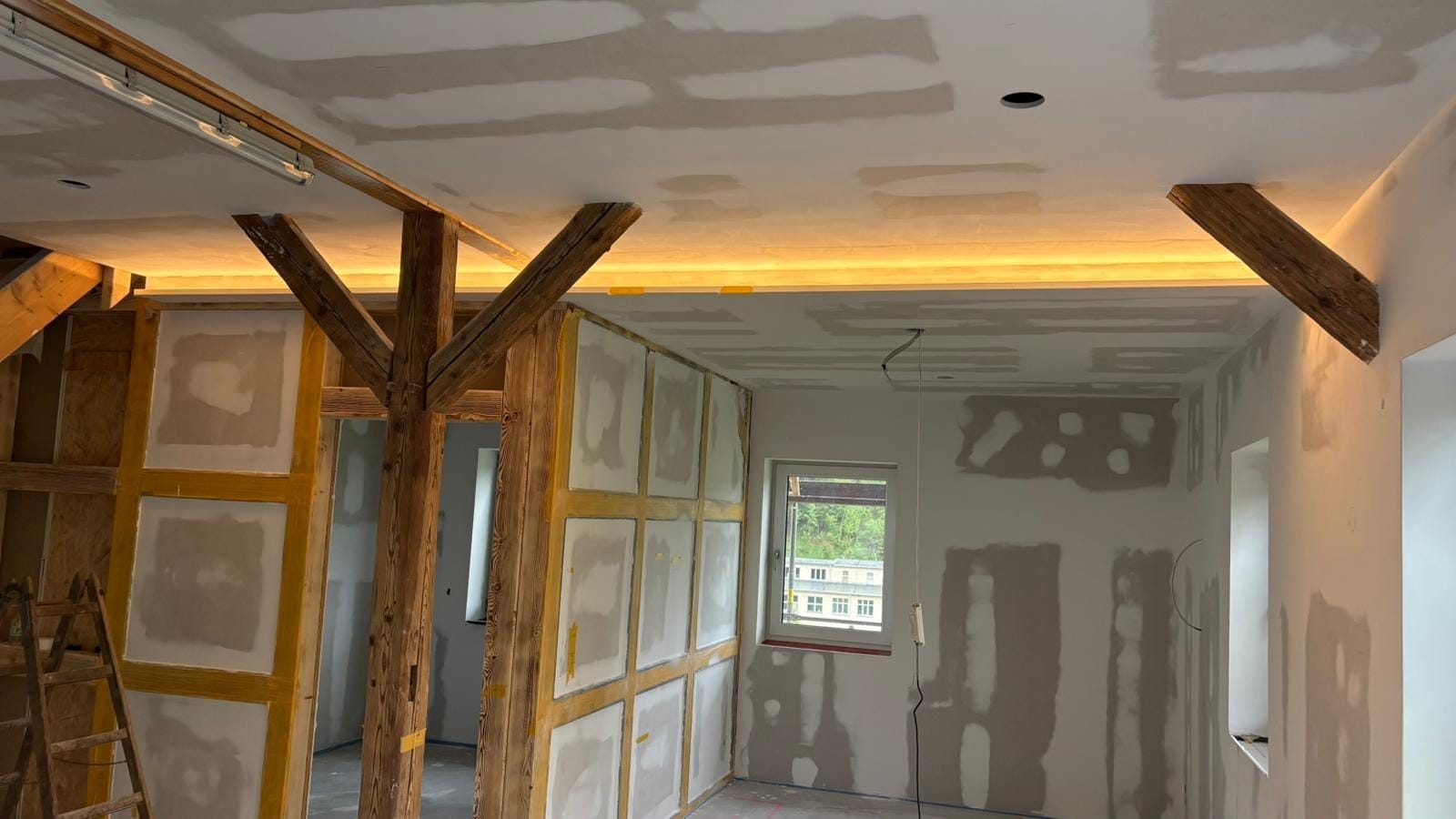 Wohnraum mit sichtbaren Holzbalken und indirekter Beleuchtung