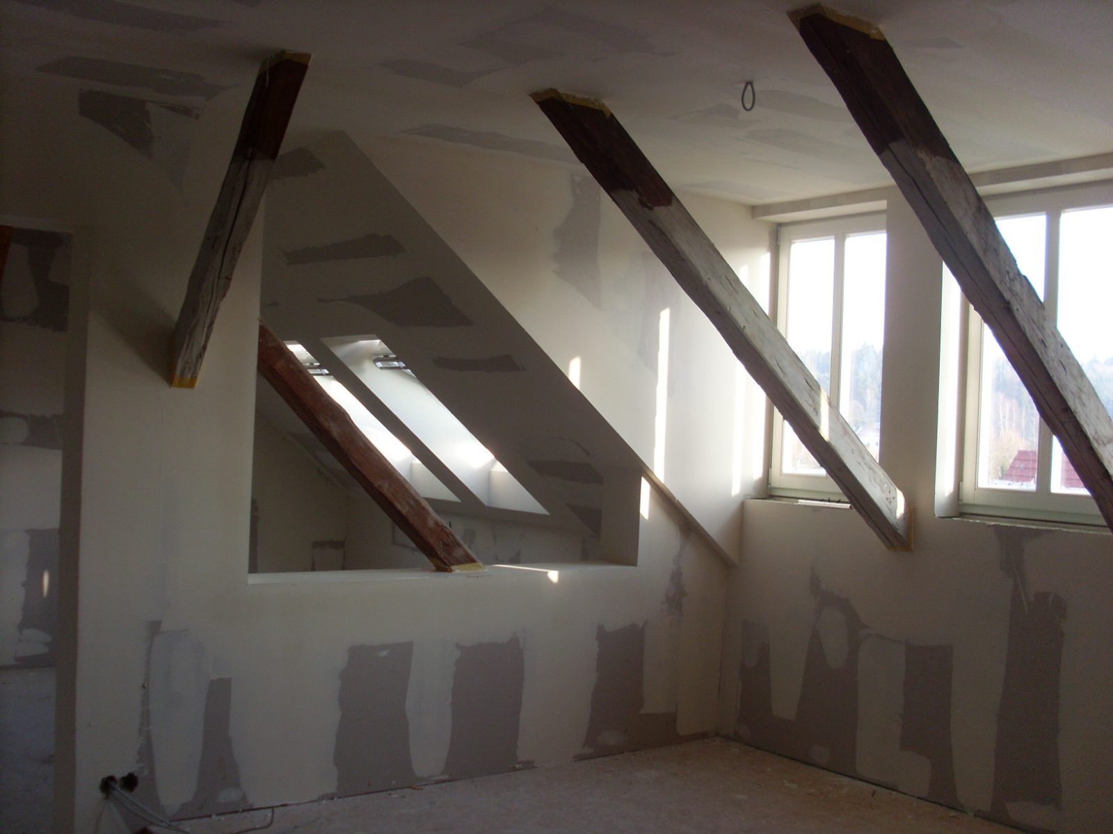 Ausgebautes Dachgeschoss mit sichtbaren Balken und verkleideten Dachschrägen